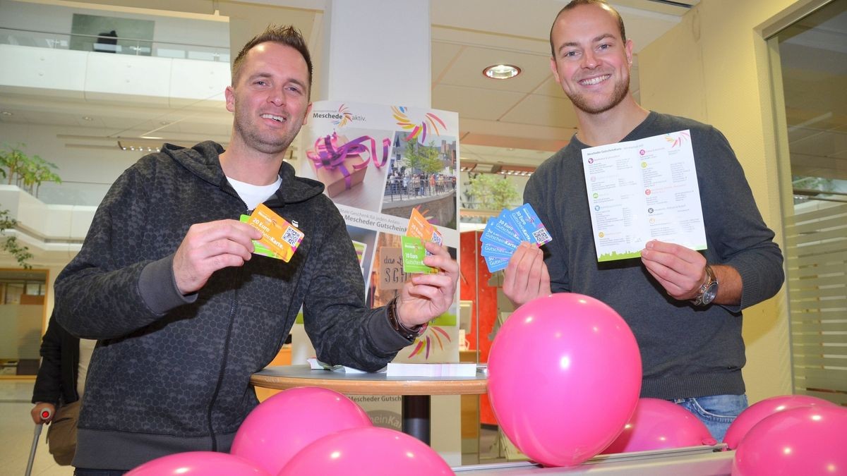 Andre Wiese, Vorsitzender der Werbegemeinschaft „Meschede aktiv“, und Christoph Hermes (rechts) vom Stadtmarketing mit dem neuen Mescheder Geschenkgutschein. Schon 84.000 Euro Umsatz sind damit gemacht worden.