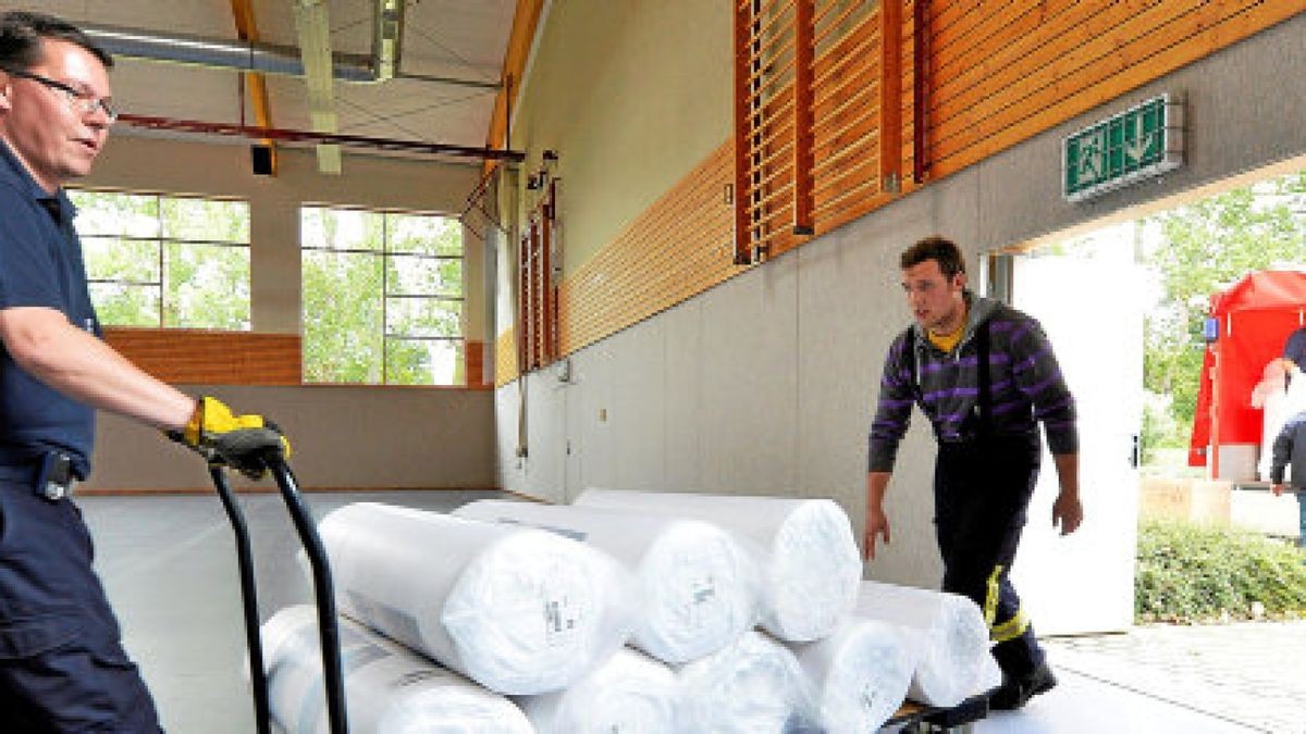 Tiefenorts Ortsbrandmeister Steffen Heller (links) und weitere Feuerwehrleute laden die Matratzen aus, auf denen die Flüchtlinge in der Notunterkunft in der Turnhalle vorübergehend schlafen Foto: Heiko Matz