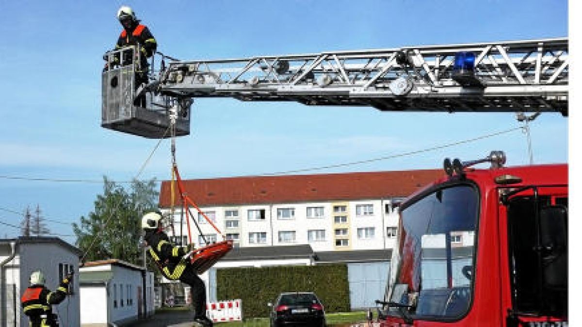 Ralf Schwartzkopf (46, im Korb), Steffen Beier (34) schwebend an der Trage, Praktikant aus der Leitstelle im Ilmkreis, und Mario Armster (57) trainieren das Bergen aus Höhen und Tiefen auf dem Hof der Berufsfeuerwehr Gotha. Foto: Ute Rang