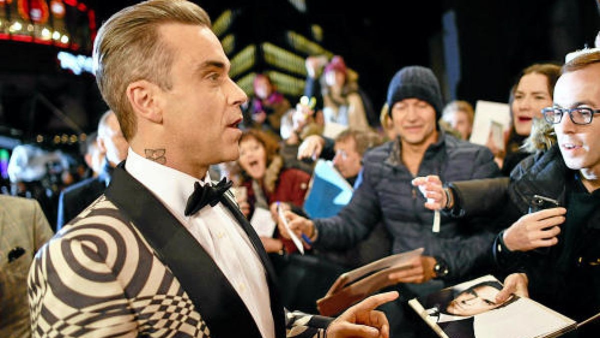 Robbie Williams schreibt am 17.11.2016 in Berlin zur 68. Verleihung des Medienpreises Bambi Autogramme für wartende Zuschauer. Foto: Jens Kalaens/dpa +++(c) dpa - Bildfunk+++