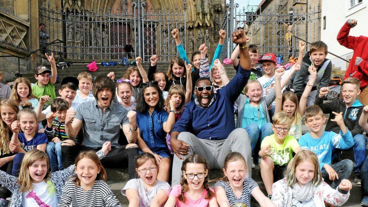 Eine Klassenfahrt ist lustig – besonders wenn man gleich am Morgen die DSDS-Stars aus dem Fernsehen trifft. Die Musiker Alexander Jahnke, Duygu Goenel und Alphonso Williams (von links) lassen sich mit den Viertklässlern der Grundschule Königsee (Landkreis Saalfeld-Rudolstadt) fotografieren. Die Erfurter Domstufen bieten dafür den richtigen Rahmen und werden kurzerhand zu einer Sangesbühne umfunktioniert.