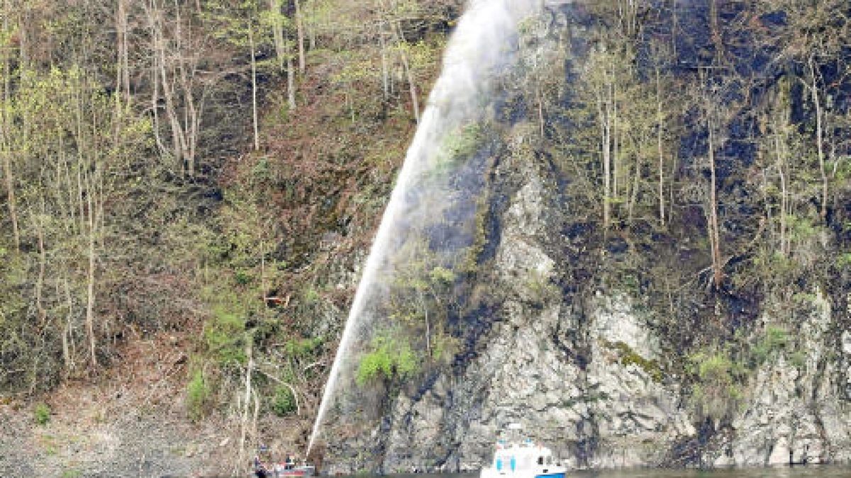 23.04.2019, Thüringen, Saaldorf: Ein Feuerwehrboot löscht einen Brand im Wald an der Bleilochtalsperre. Der Brand am Heinrichstein bei Saalburg-Ebersdorf im Saale-Orla-Kreis ist erneut ausgebrochen. Neben Feuerwehrkräften aus dem Saale-Orla-Kreis sind auch Rettungskräfte und Technisches Hilfswerk aus Oberfranken im Einsatz. Foto: Bodo Schackow/dpa-Zentralbild/dpa +++ dpa-Bildfunk +++