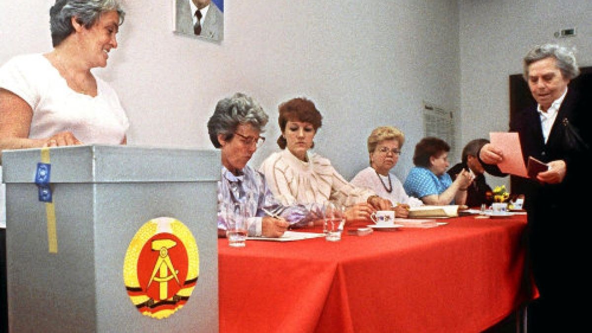 Erich Honecker lächelt von der Wand, auf der Urne prangen Hammer und Zirkel im Ährenkranz, der Stimmzettel ist schnell gefaltet: Wahlszene vom 7. Mai 1989 in Ost-Berlin.Foto: Roland Holschneider/DPA