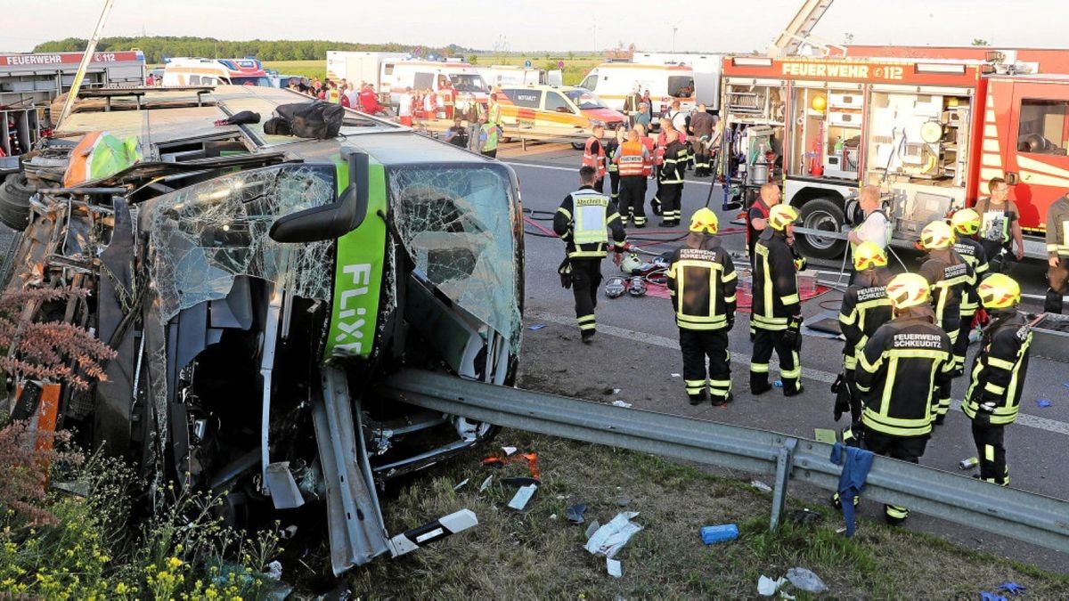 Einsatzkräfte der Feuerwehr stehen an der Unfallstelle auf der A9 neben dem verunglückten Bus.