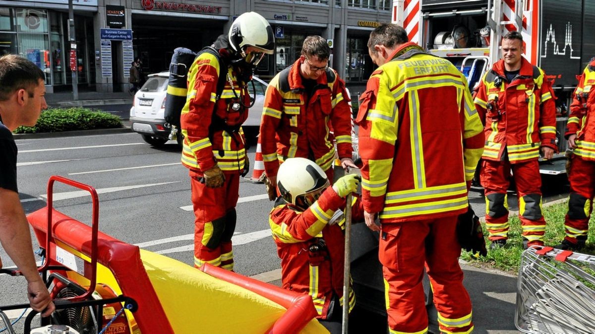 Kameraden der Berufsfeuerwehr steigen mit Atemschutz in die Tiefe, um gegen den unterirdischen Kabelbrand am Juri-Gagarin-Ring