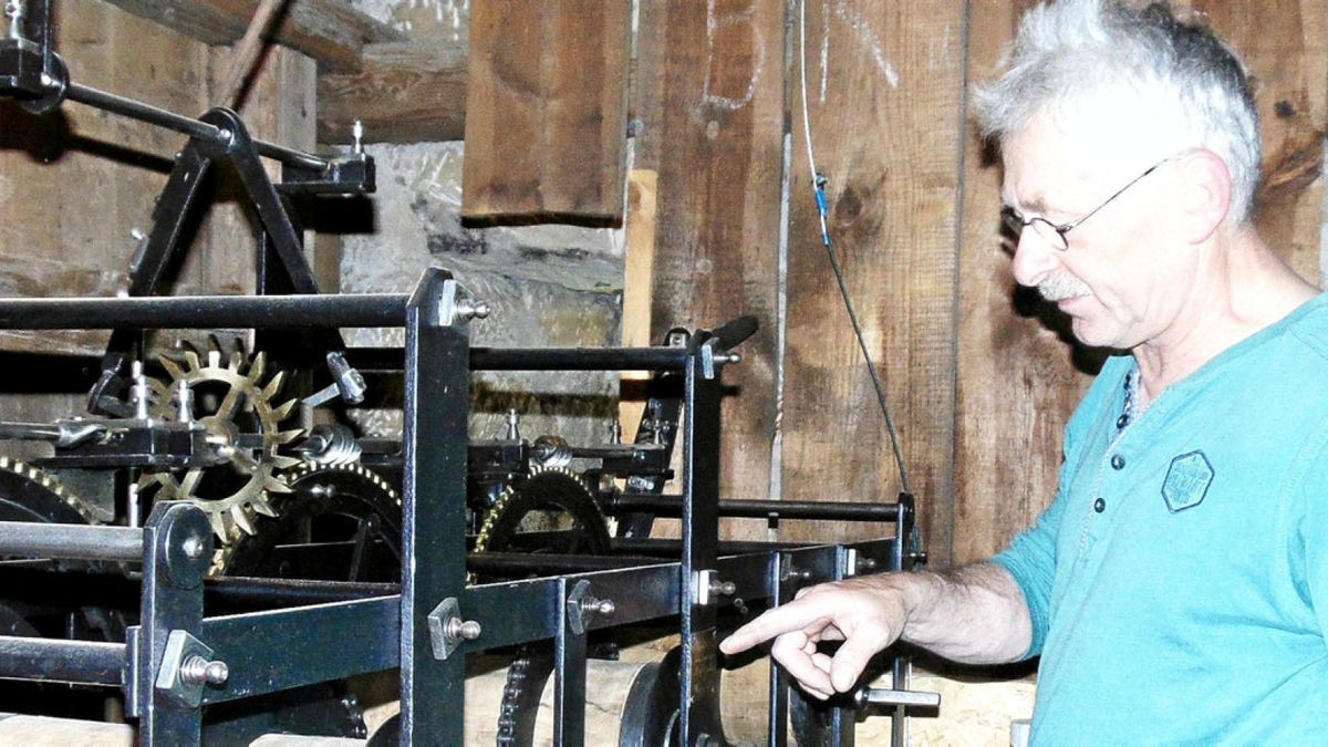 Dieter Hoffmann steht am restaurierten mechanischen Uhrwerk der Kirchturmuhr.