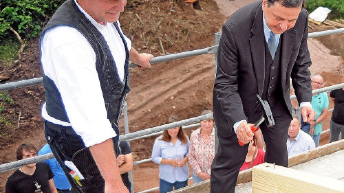 Zimmerermeister Hartmut Henfling von der Firma Alpha aus Erfurt beobachtet, wie SWG-Geschäftsführer Wilhelm G. Wagner beim Richtfest einen Nagel in den Sparren schlägt. Unten verfolgen am Bau beteiligte Foto: Jensen Zlotowicz