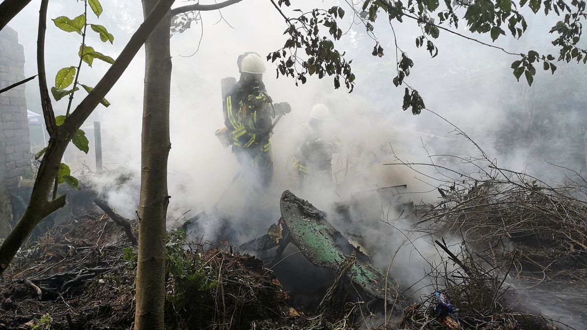 Die Feuerwehr löscht den Brand in einer Gartenanlage