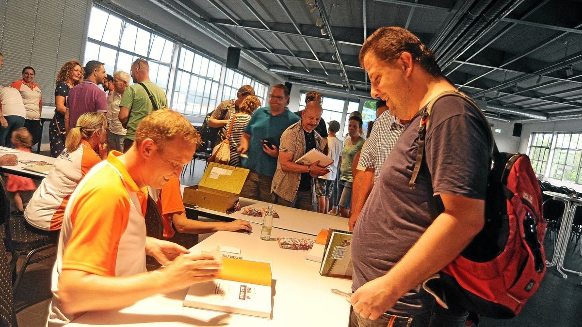 Autor und Heimweh-Vorsitzender Enrico Martin signiert im Saal des Museums Automobile Welt Käufern wie Frank Rothe sein Buch „Heimweh – das Buch“.­