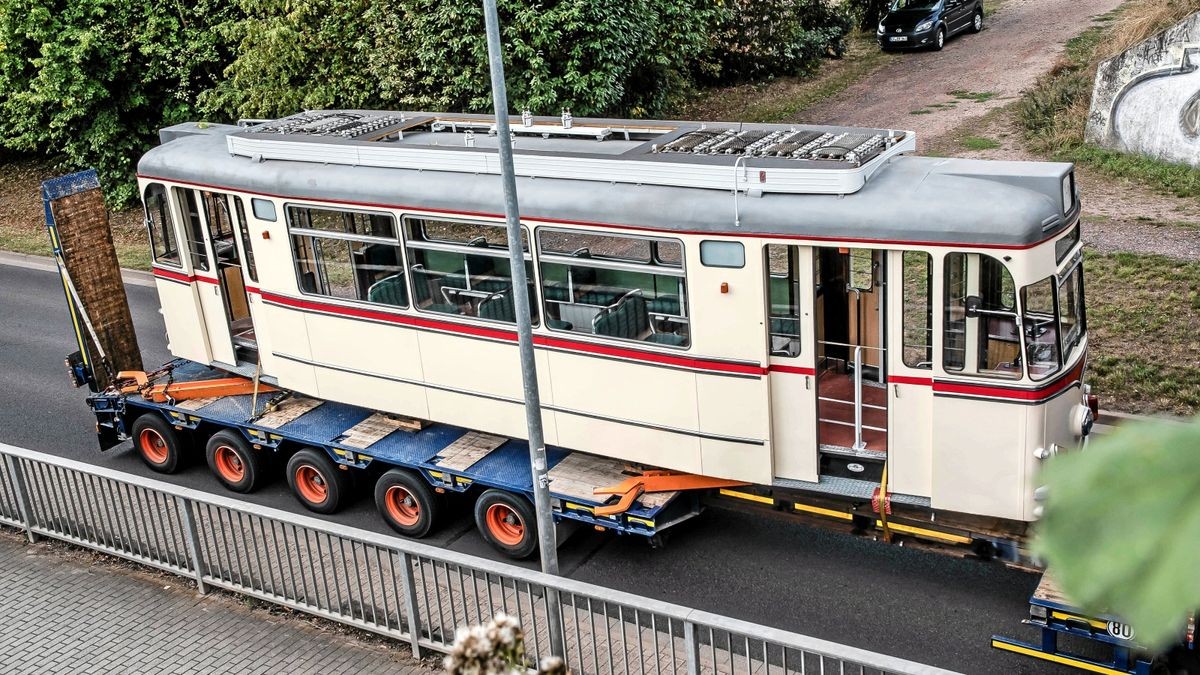 Der Triebwagen 47 fährt auf einem Tieflader der Firma Universal-Transporte durch die Krusewitzstraße und passiert die Eisenbahn-Brücke.