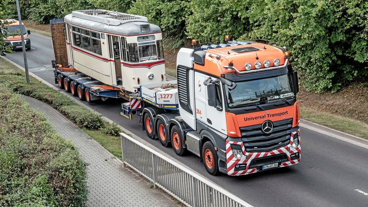 Der Triebwagen 47 fährt auf einem Tieflader der Firma Universal-Transporte durch die Krusewitzstraße und passiert die Eisenbahn-Brücke.