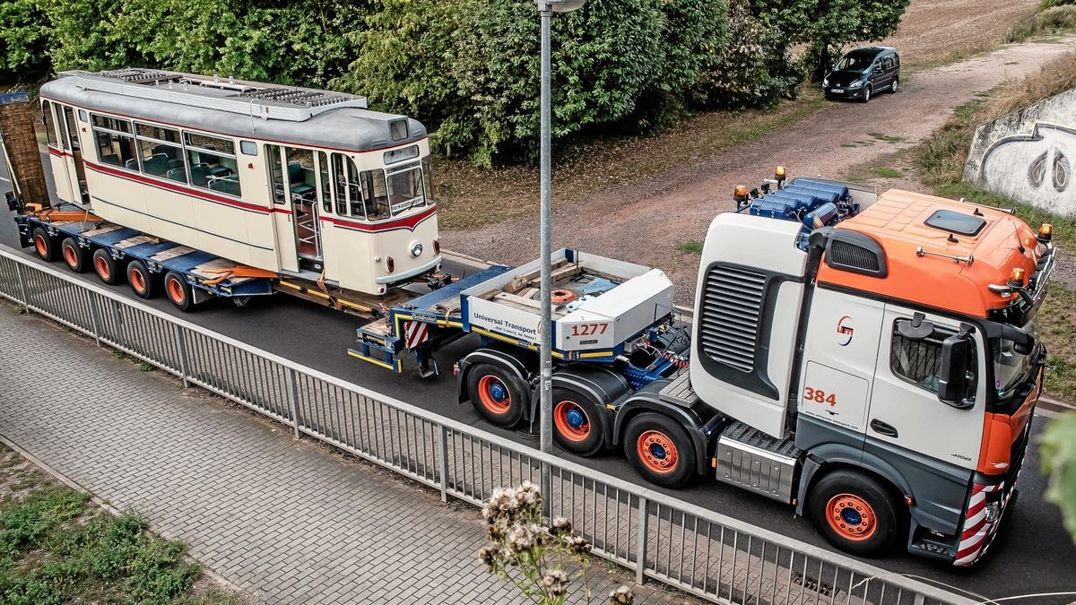 Der Triebwagen 47 fährt auf einem Tieflader der Firma Universal-Transporte durch die Krusewitzstraße und passiert die Eisenbahn-Brücke.