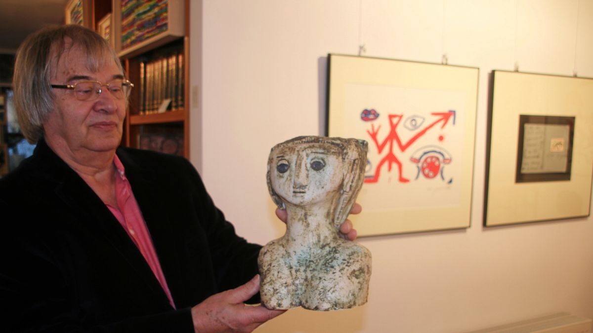 Volker Grahn hält eine Keramik-Plastik von Petra Arndt mit dem Titel „Picasso, wo bist du“. Ihre Arbeiten korrespondieren in der Galerie mit Druckgrafiken von A. R. Penck.