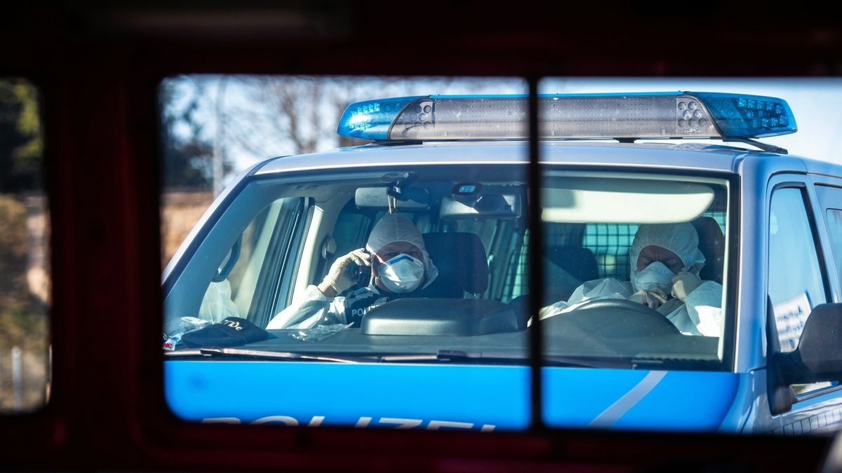 Polizisten warten in Vollschutzanzügen am Ortseingang von Neustadt am Rennsteig.  