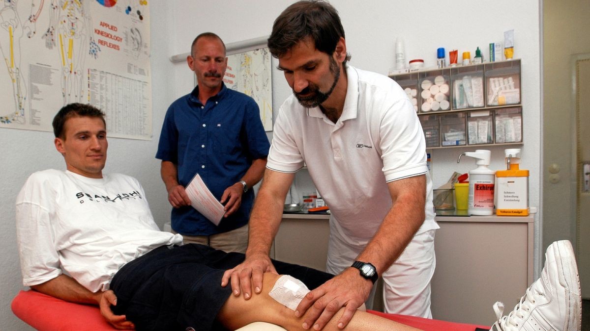 Dr. Frank-Detlef Stanek untersucht das Knie von Basketballer Oliver Braun. Physiotherapeut Andreas Krause betreut den Sportler in seiner Praxis.