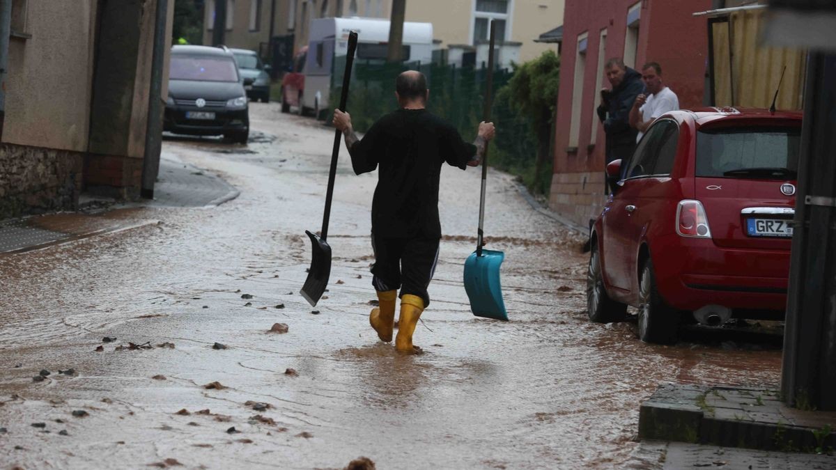 Die Feuerwehr versucht am Freitag, den überfluteten Rathenauplatz in Zeulenroda-Triebes von Unrat zu befreien. Nach einem heftigen Gewitter sind Wasser und Geröll von Feldern in die Stadt geflossen. Auch Anwohner helfen mit.