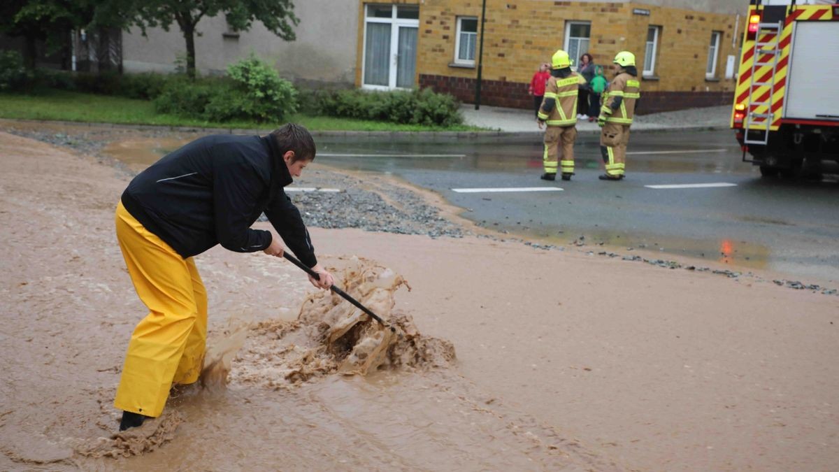 Die Feuerwehr versucht am Freitag, den überfluteten Rathenauplatz in Zeulenroda-Triebes von Unrat zu befreien. Nach einem heftigen Gewitter sind Wasser und Geröll von Feldern in die Stadt geflossen. Auch Anwohner helfen mit.