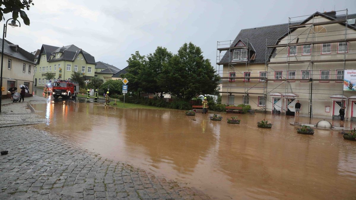 Die Feuerwehr versucht am Freitag, den überfluteten Rathenauplatz in Zeulenroda-Triebes von Unrat zu befreien. Nach einem heftigen Gewitter sind Wasser und Geröll von Feldern in die Stadt geflossen. Auch Anwohner helfen mit.