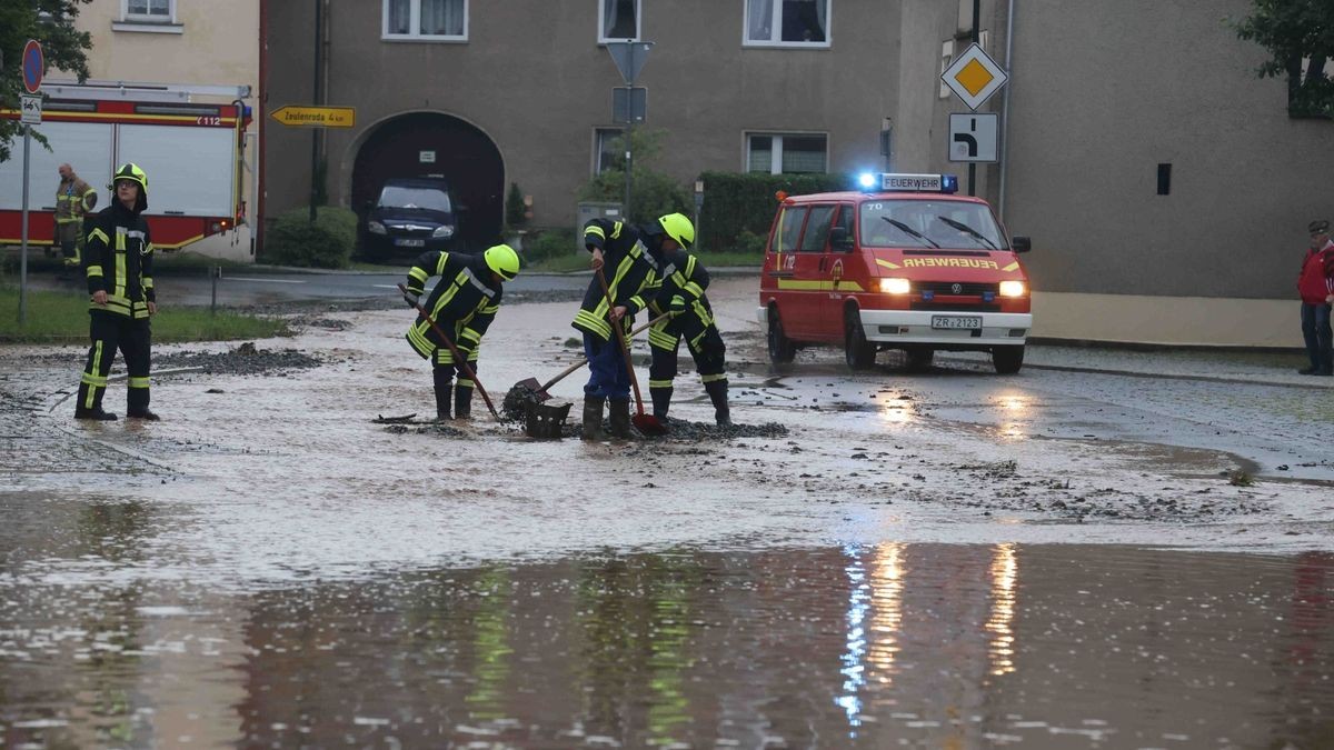 Die Feuerwehr versucht am Freitag, den überfluteten Rathenauplatz in Zeulenroda-Triebes von Unrat zu befreien. Nach einem heftigen Gewitter sind Wasser und Geröll von Feldern in die Stadt geflossen. Auch Anwohner helfen mit.