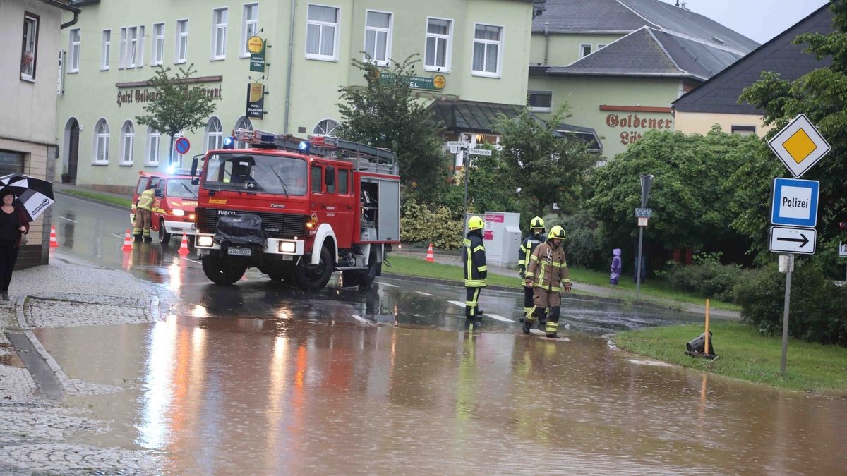 Die Feuerwehr versucht am Freitag, den überfluteten Rathenauplatz in Zeulenroda-Triebes von Unrat zu befreien. Nach einem heftigen Gewitter sind Wasser und Geröll von Feldern in die Stadt geflossen. Auch Anwohner helfen mit.