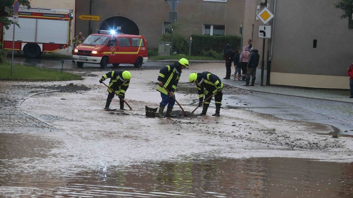 Die Feuerwehr versucht am Freitag, den überfluteten Rathenauplatz in Zeulenroda-Triebes von Unrat zu befreien. Nach einem heftigen Gewitter sind Wasser und Geröll von Feldern in die Stadt geflossen. Auch Anwohner helfen mit.