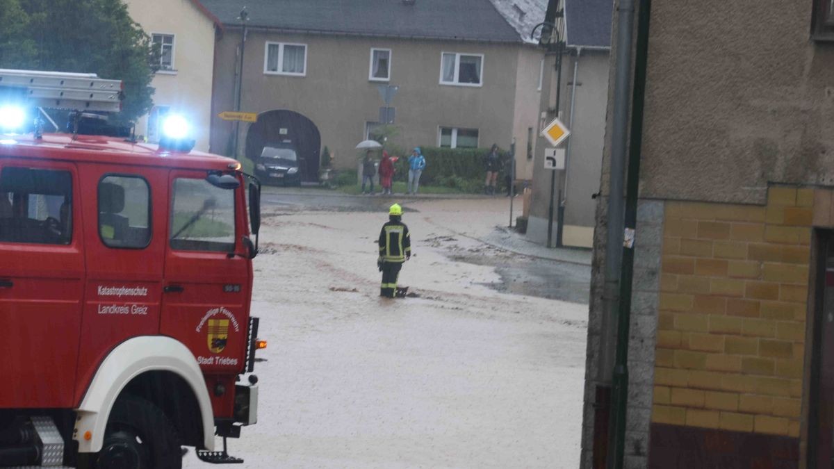 Die Feuerwehr versucht am Freitag, den überfluteten Rathenauplatz in Zeulenroda-Triebes von Unrat zu befreien. Nach einem heftigen Gewitter sind Wasser und Geröll von Feldern in die Stadt geflossen. Auch Anwohner helfen mit.