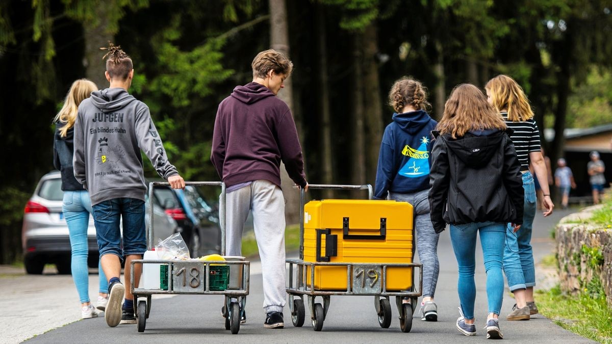 Eine Schülergruppe bringt während einer Klassenfahrt einen Transportwagen mit Essen in ihre Unterkunft.