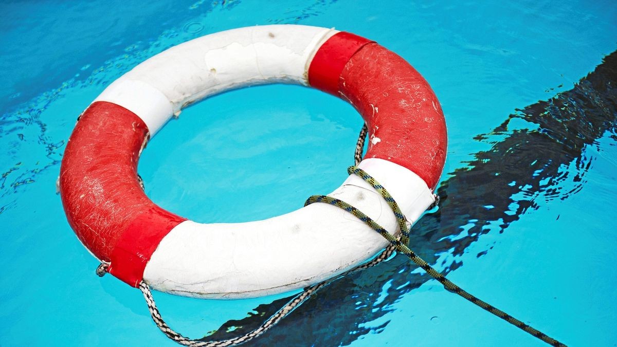 Ein Rettungsring liegt in einem Freibad im Wasser.