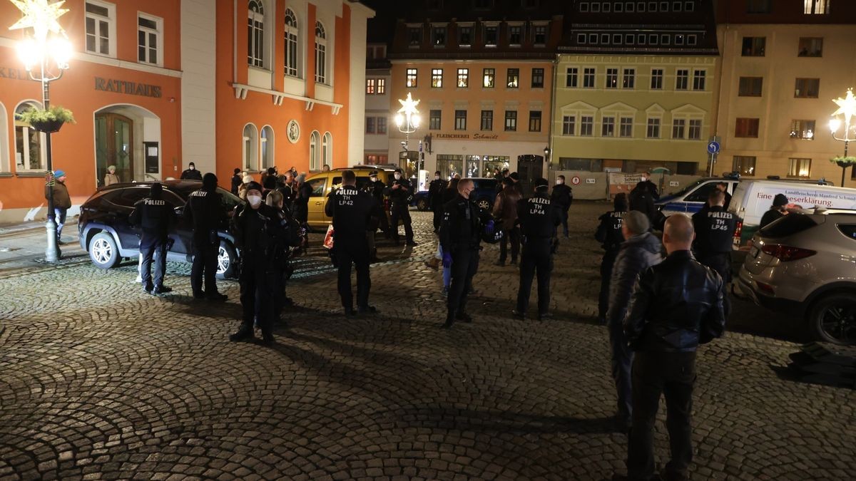 Polizeibeamte kontrollieren auf dem Marktplatz von Kahla eine Gruppe von etwa 25 Menschen, die an einem sogenannten Spaziergang gegen die Corona-Maßnahmen teilgenommen haben. 