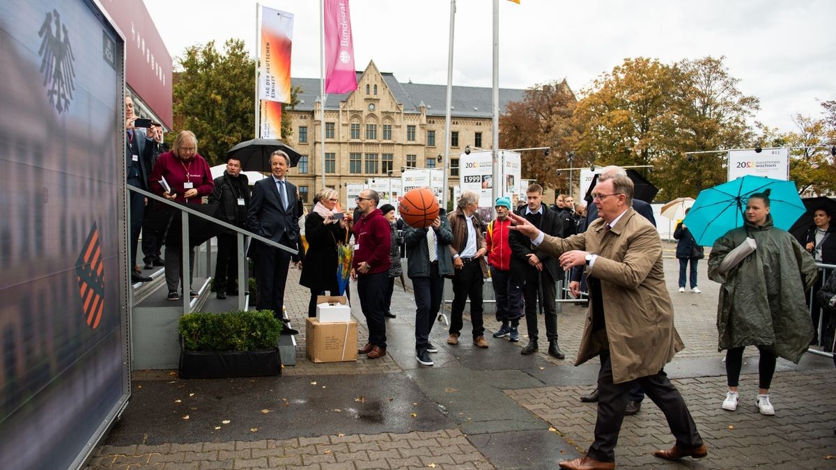 Ministerpräsident Bodo Ramelow (Die Linke) wirft einen Ball bei einem Spiel am Stand des Bundesrates auf dem Domplatz zu Beginn der Feierlichkeiten zum Tag der Deutschen Einheit.