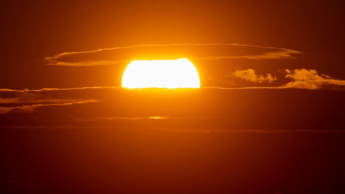 14. November: Die untergehende Sonne zwischen Wolken am Horizont in Straussfurt.