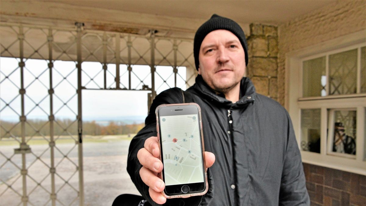 Autor Jens-Uwe Fischer präsentiert den App-basierten Audiowalk zu Franz Ehrlich in der Gedenkstätte Buchenwald. Eine Station ist das vom Bauhäusler Ehrlich entworfene Lagertor mit der Inschrift 