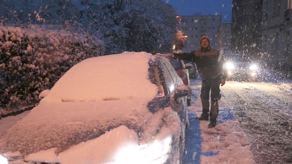 Thomas Herrmann räumt in Gera-Langenberg sein zugeschneites Auto frei.