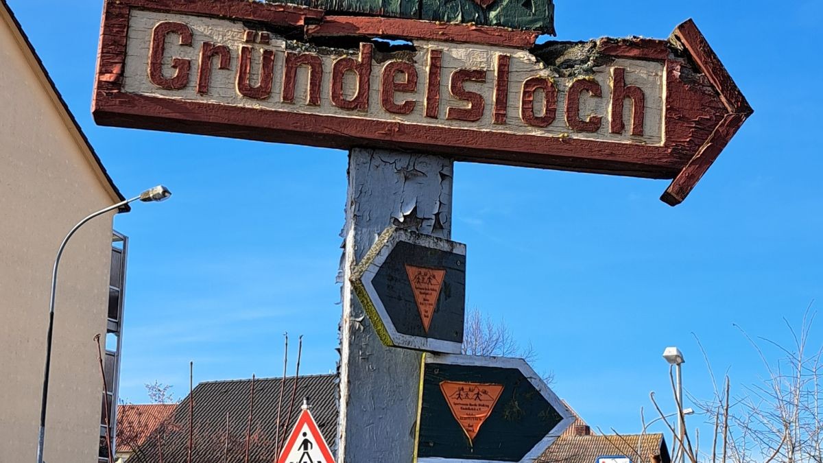 Ein historisches Schnitzwerk weist den Weg zum Gründelsloch.