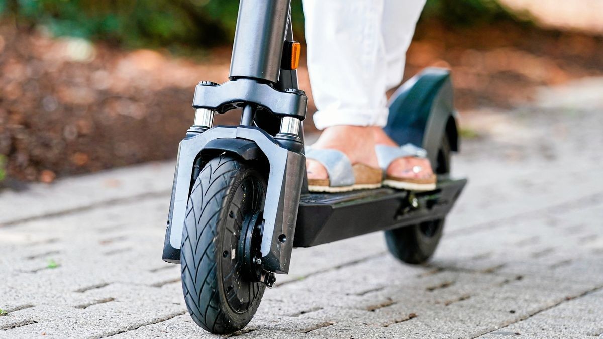 Eine Frau fährt einen E-Scooter auf einem Fuß- und Radweg.