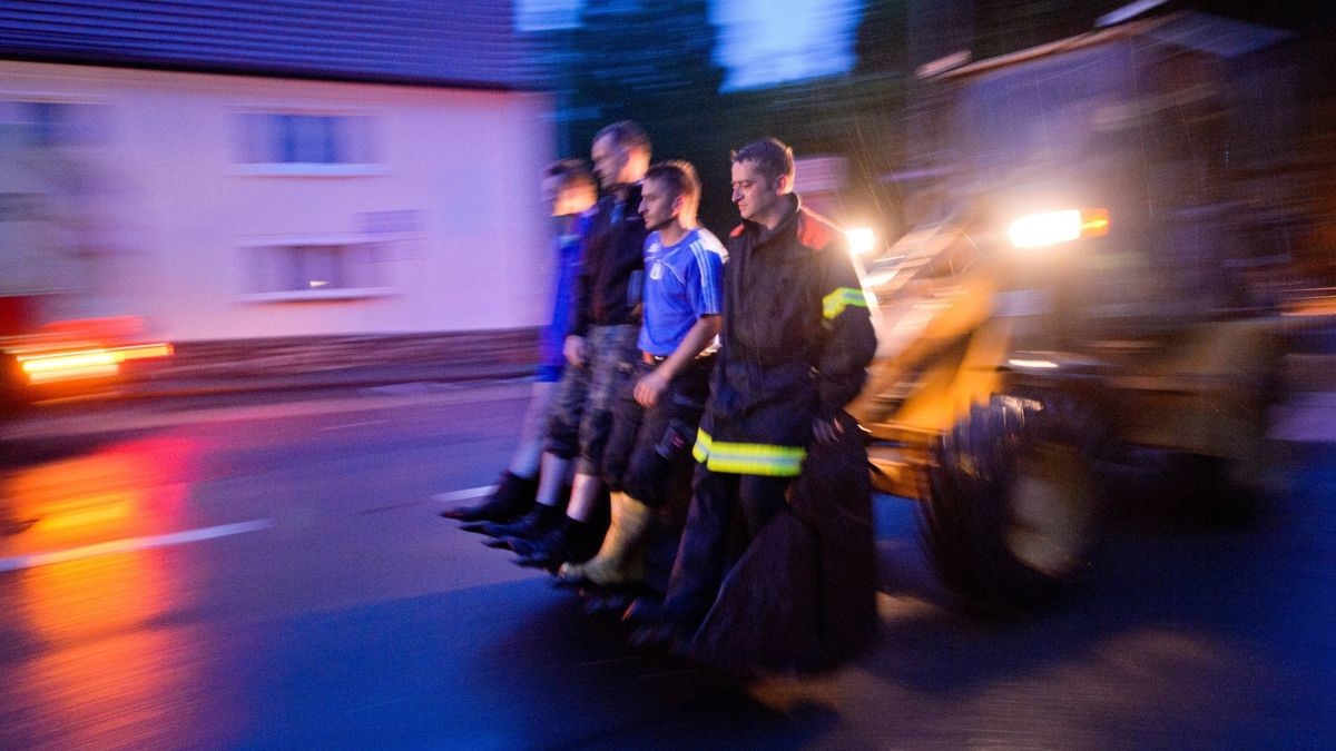 Helfer werden am mit einem Bagger durch das Hochwasser gefahren im Ortskern von Büssleben 