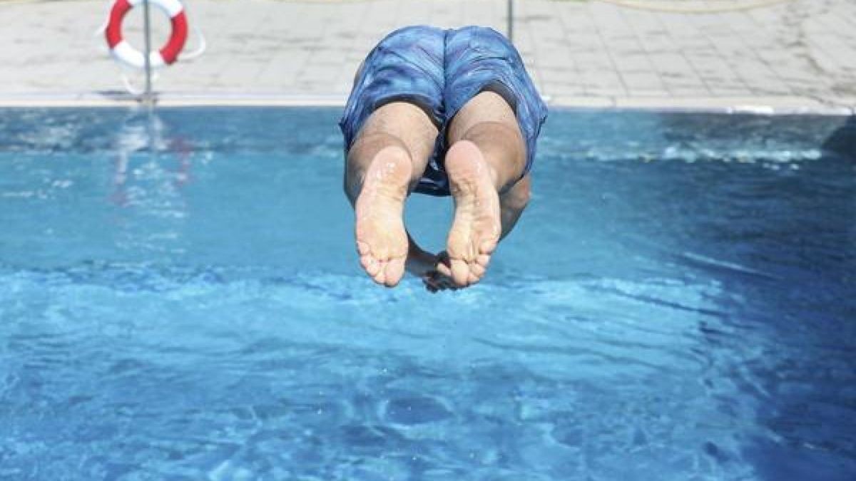 Ein Mann springt von einem Sprungbrett kopfüber ins Wasser. (Archivbild)