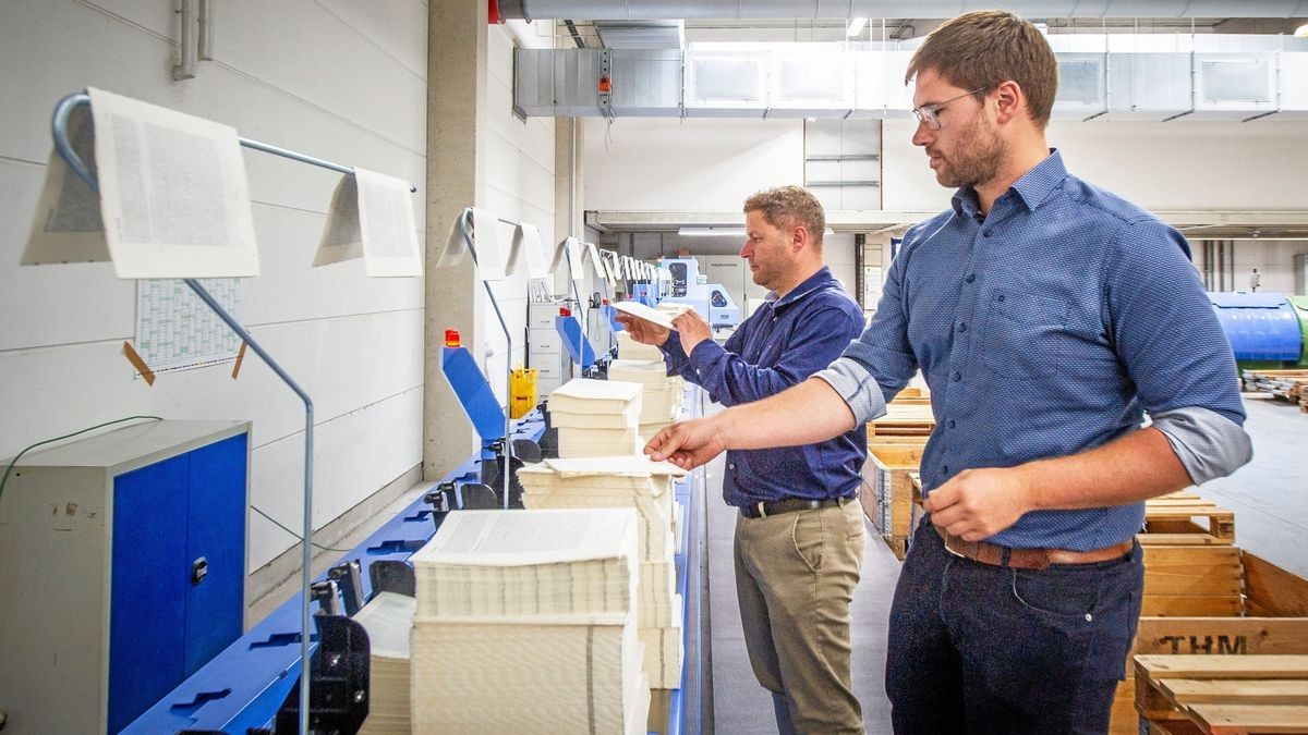 Blick in die Produktion, in der sich sowohl Druckerei als auch Buchbinderei befinden. Michael Tuchscher und Max Herrmann (von links) van der neuen Technik.