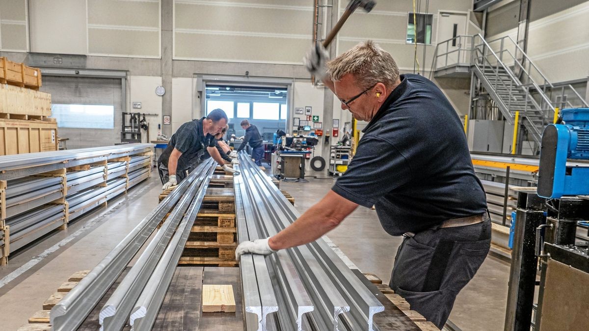 Arbeiten für den Eisenbahnbau: Mit einem Hammer werden die Gleisteile zum Einrasten ins Fundament geklopft. Zuvor mussten die Gleise gemeinsam angepackt und zurecht gedreht werden. 