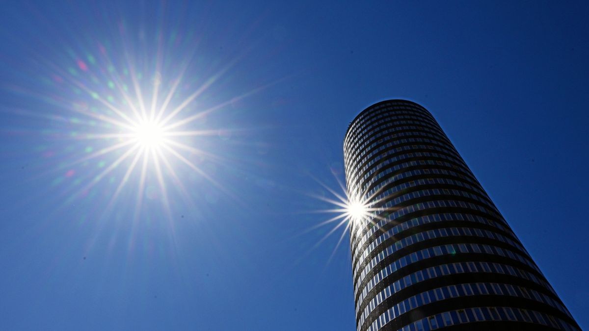 Die Sonne scheint vom wolkenlosen Himmel und spiegelt sich in Jena im Glas des Jentower.