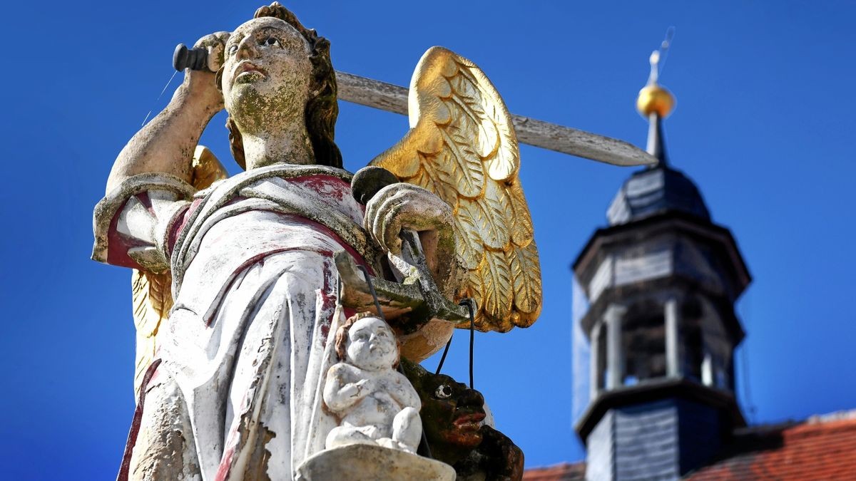 Erzengel Michael auf dem Marktbrunnnen vor dem Rathaus in Buttstädt. In seiner linken Hand trägt er die Waage, auf deren einer Schale das Kind schwerer wiegt als der Teufel mitsamt Mühlstein.