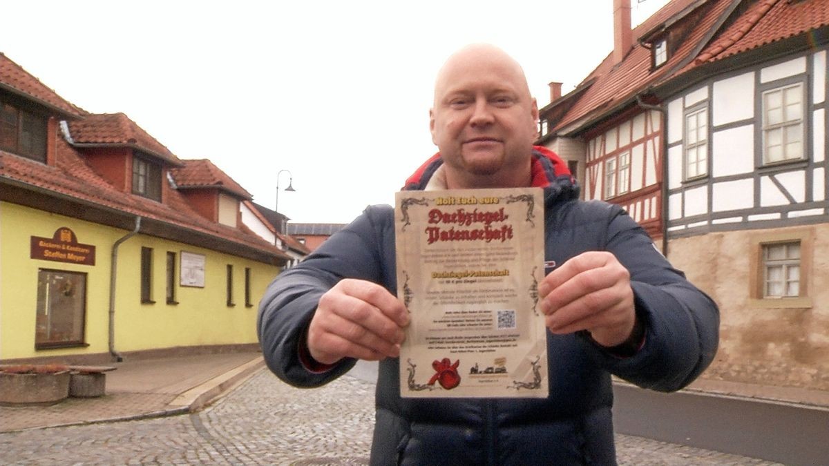 David John hält eine Dachziegel-Patenschaftsurkunde. Deren Erwerb soll zum Erhalt der Dorfschänke Ingersleben beitragen.