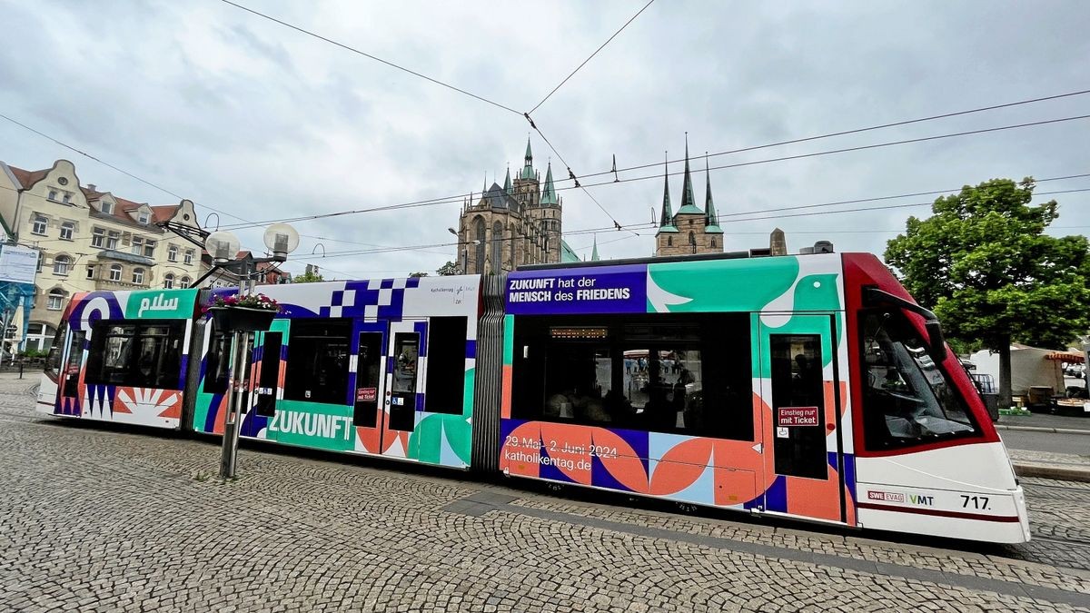 Eine Straßenbahn mit Werbung für den Deutschen Katholikentag fährt über den Domplatz. Ab 29. Mai werden Tausende Teilnehmer in Erfurt erwartet.