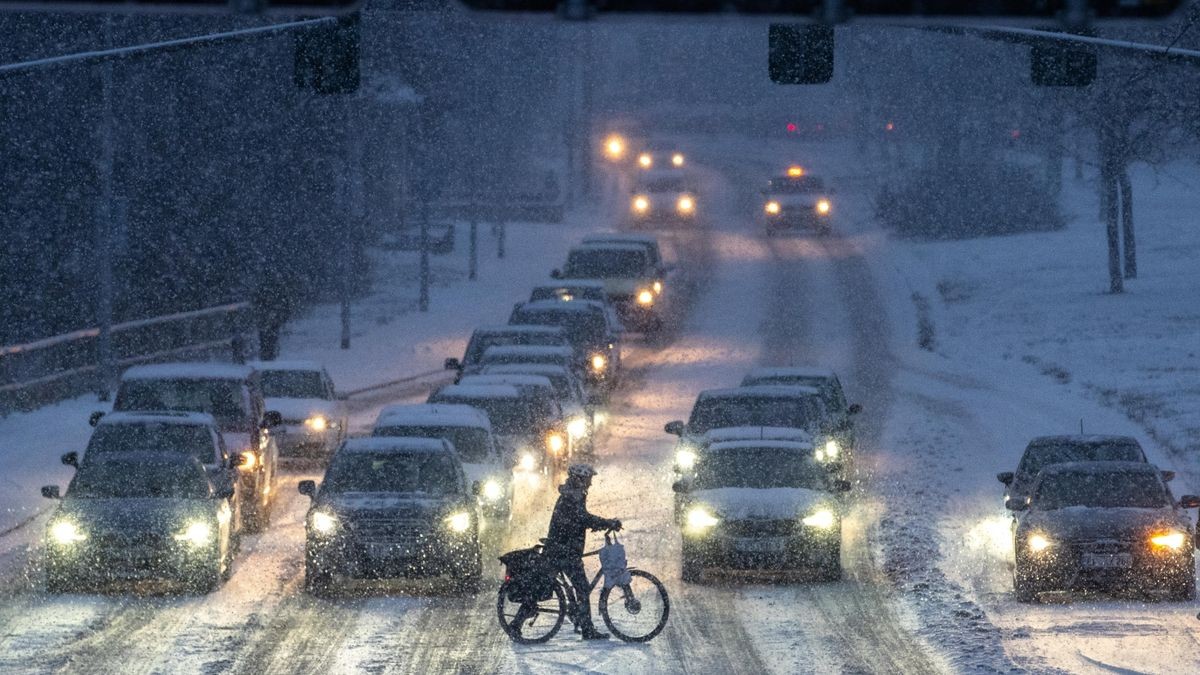 Ein Radfahrer schiebt am späten Nachmittag sein Rad über die verschneite Erfurter Staufenbergallee.