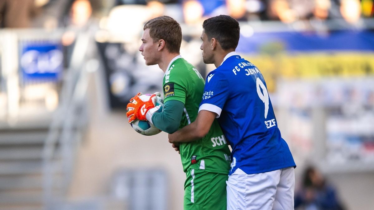 Torhüter Lukas Schellenberg (FC Rot-Weiß Erfurt) wird von Cemal Sezer (FC Carl Zeiss Jena) festgehalten.