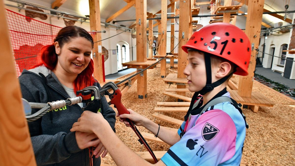Trainerin Greta Erb erläutert dem Jungen Yannick Schlicht, wie man sich in den Kletterstrecken sicher bewegt.