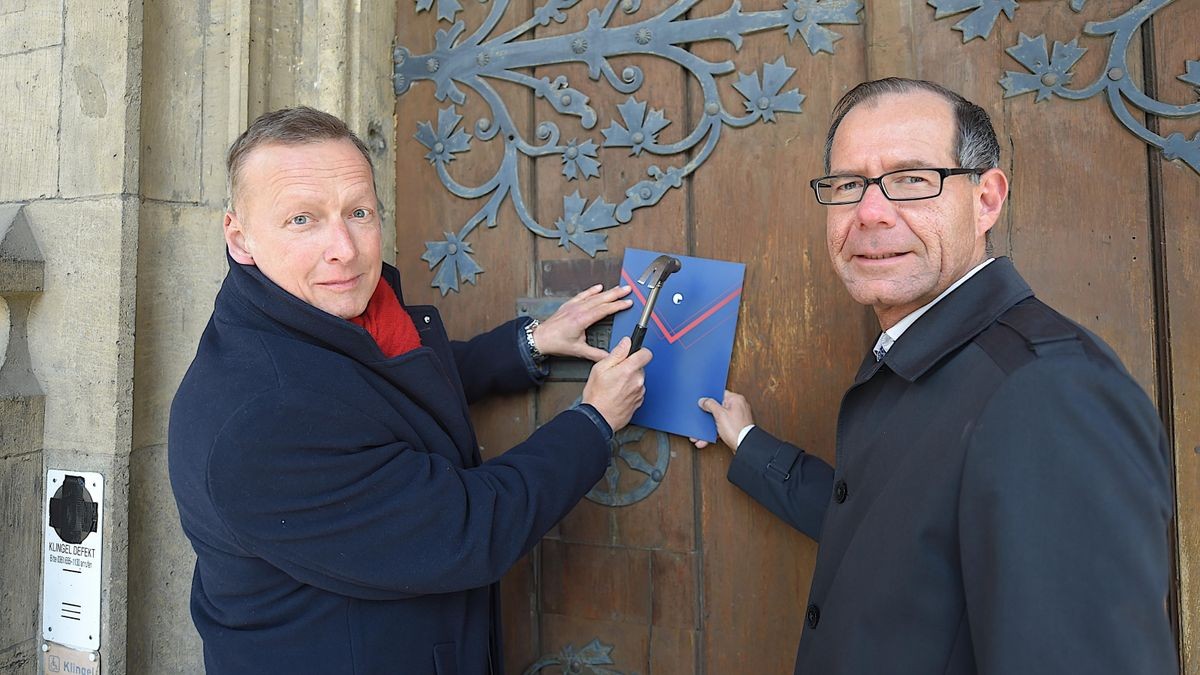 Vorstandschef Christian Büttner (links) und Vorstand Christian Gottschalk von der WBG „Einheit“ nageln ihre Thesen zum bezahlbaren Wohnungsbau an die Erfurter Rathaustür.