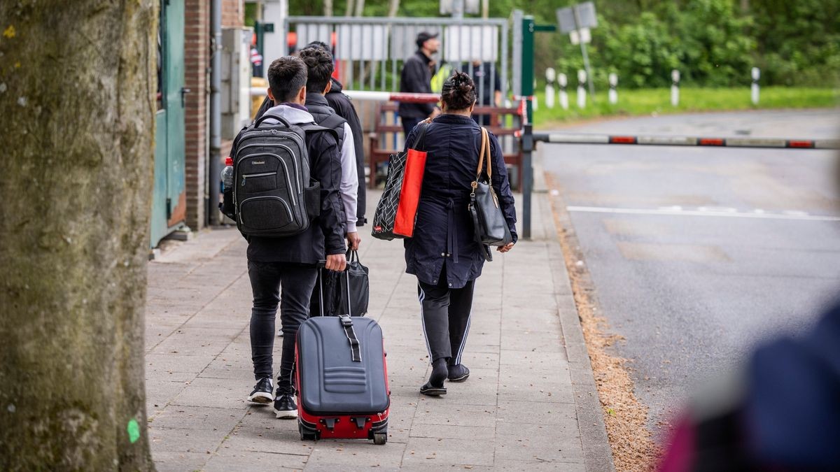 Flüchtlinge stehen mit Gepäck am Eingang einer Flüchtlingsunterkunft.