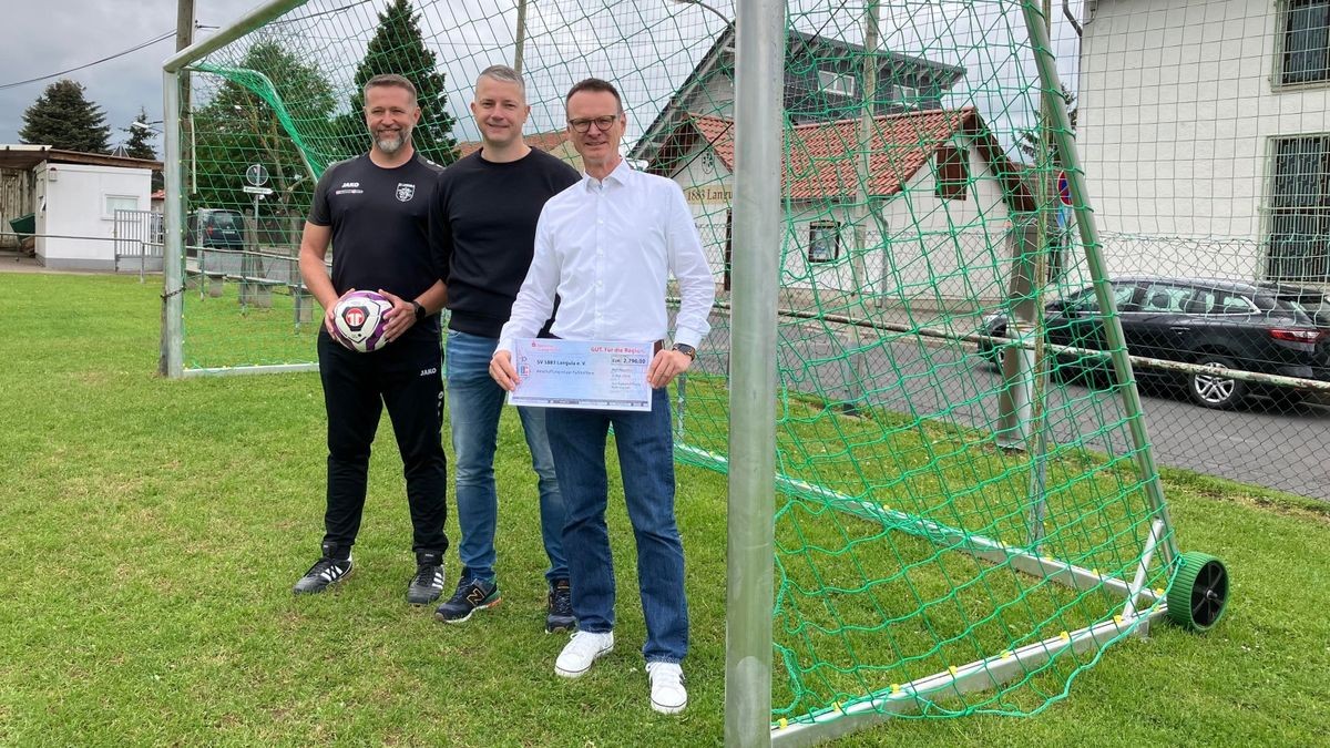 Ronny Karmrodt, Peter Hirschfeld und Torsten Gräbedünkel vom SV 1883 Langula freuen sich über den Scheck der Sparkassenstiftung. Sie stehen vor einem kleinen mobilen Tor für die Kindermannschaften auf dem Langulaer Sportplatz. Von dem Geld sollen zwei neue große Tore angeschafft werden.