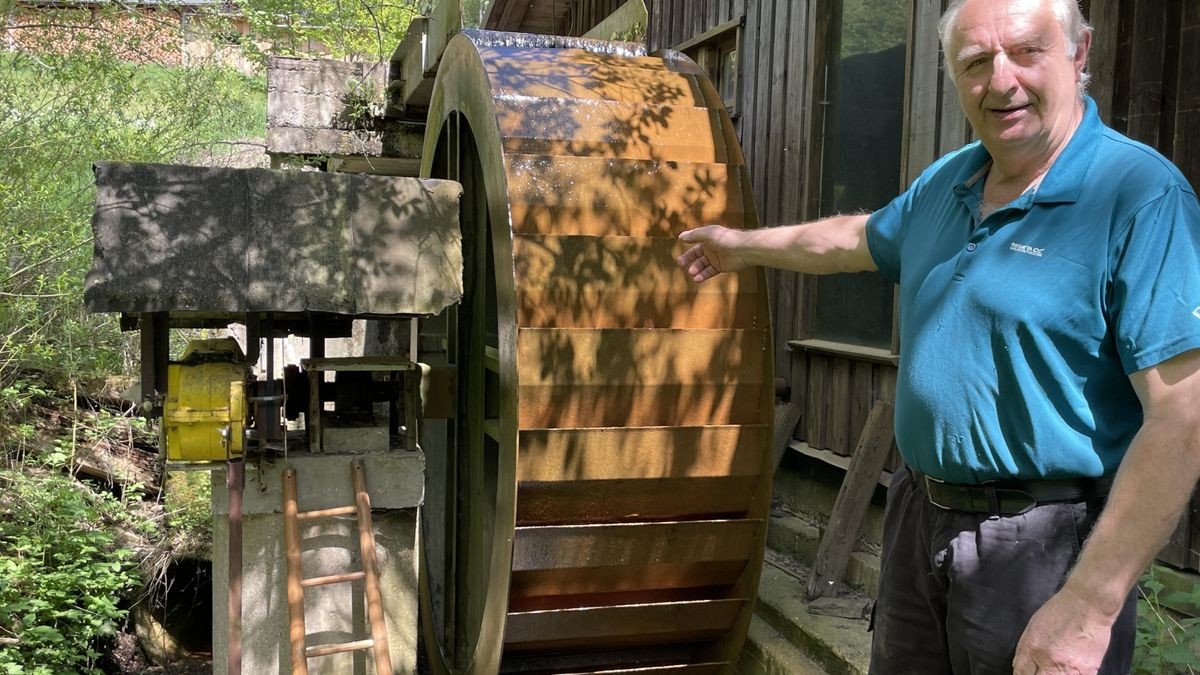 Manfred Griebel am Wasserrad. Es treibt die nachgebildete historische Mühlentechnik im Nebengebäude an.